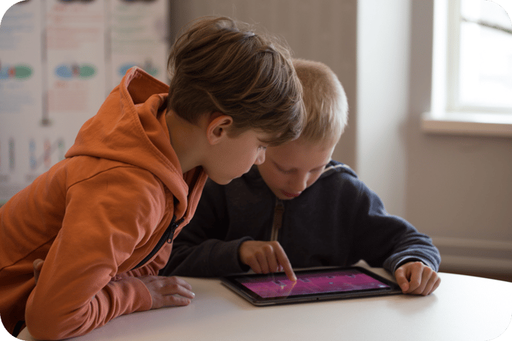 Two boys using Moomin Language School on a tablet Two boys using Moomin Language School on a tablet